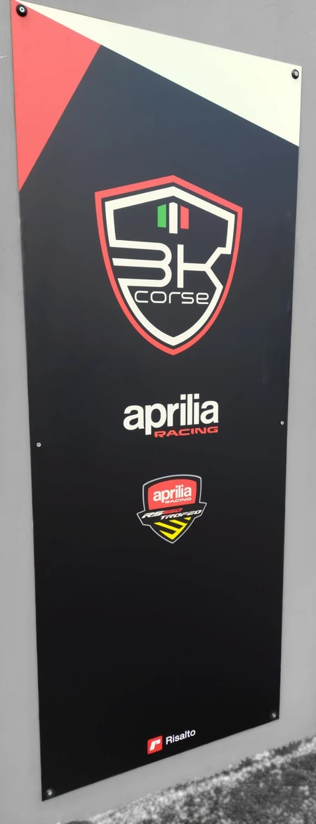 Insegna in Dibond® stretta e alta fissata a muro, in tinta nera con dettagli bianchi e rossi e il logo di "BK Corse"
